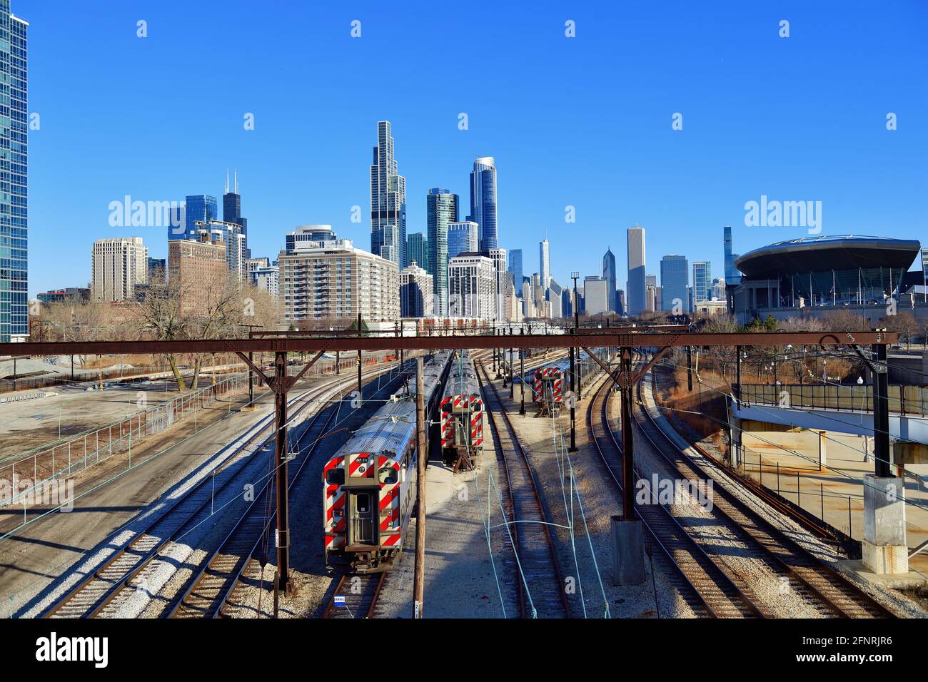 Chicago, Illinois, USA. Die dynamische Skyline der Stadt zeichnet sich ab, und die Metra-Pendlerzüge sitzen untätig auf einem Lagerplatz auf der nahe Südseite der Stadt. Stockfoto