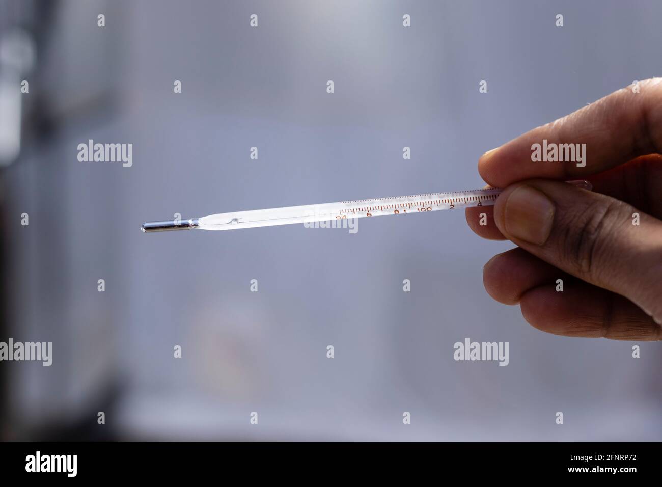 Selektiver Fokus auf ein analoges Thermometer, das in menschlicher Hand gehalten wird Stockfoto