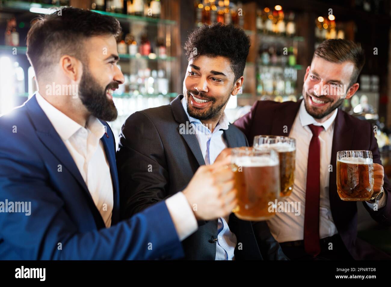 Menschen-, Freundschafts- und Festkonzept. Fröhliche Geschäftsleute, männliche Freunde, die Bier in der Kneipe trinken Stockfoto