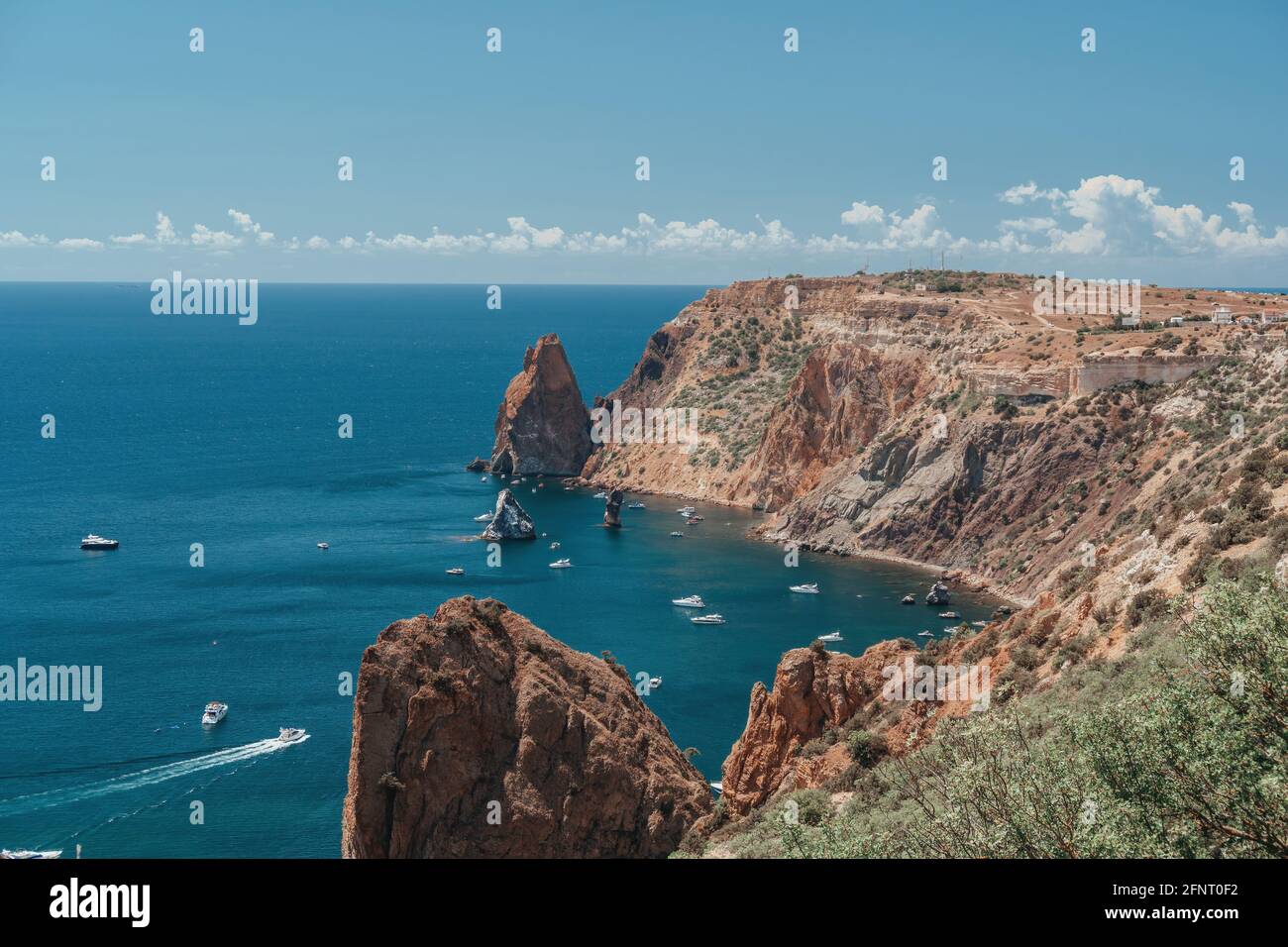 Boote und Yachten in der felsigen Bucht mit kristallklarem azurblauem Meer an einem sonnigen Tag. Ruhiges Meer vor dem Hintergrund vulkanischer felsiger Küsten. Das Konzept eines Stockfoto