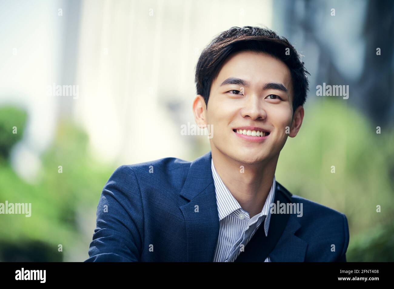 Outdoor-Porträt eines erfolgreichen asiatischen Geschäftsmann glücklich und Lächelnd Stockfoto
