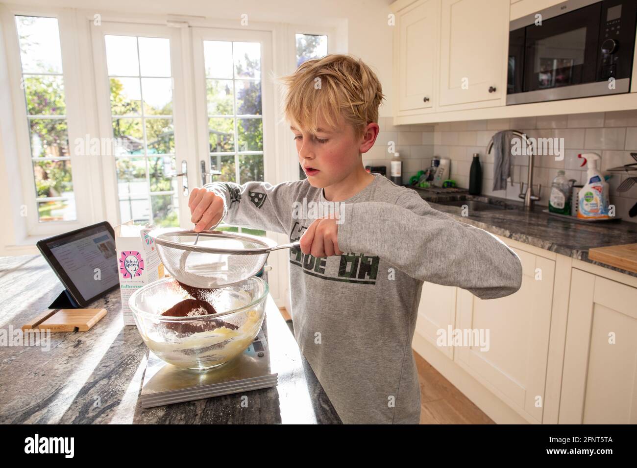 10-jähriger Junge bereitet Zutaten für den Schokoladenkuchen zu Hause, England, Großbritannien, zu Stockfoto