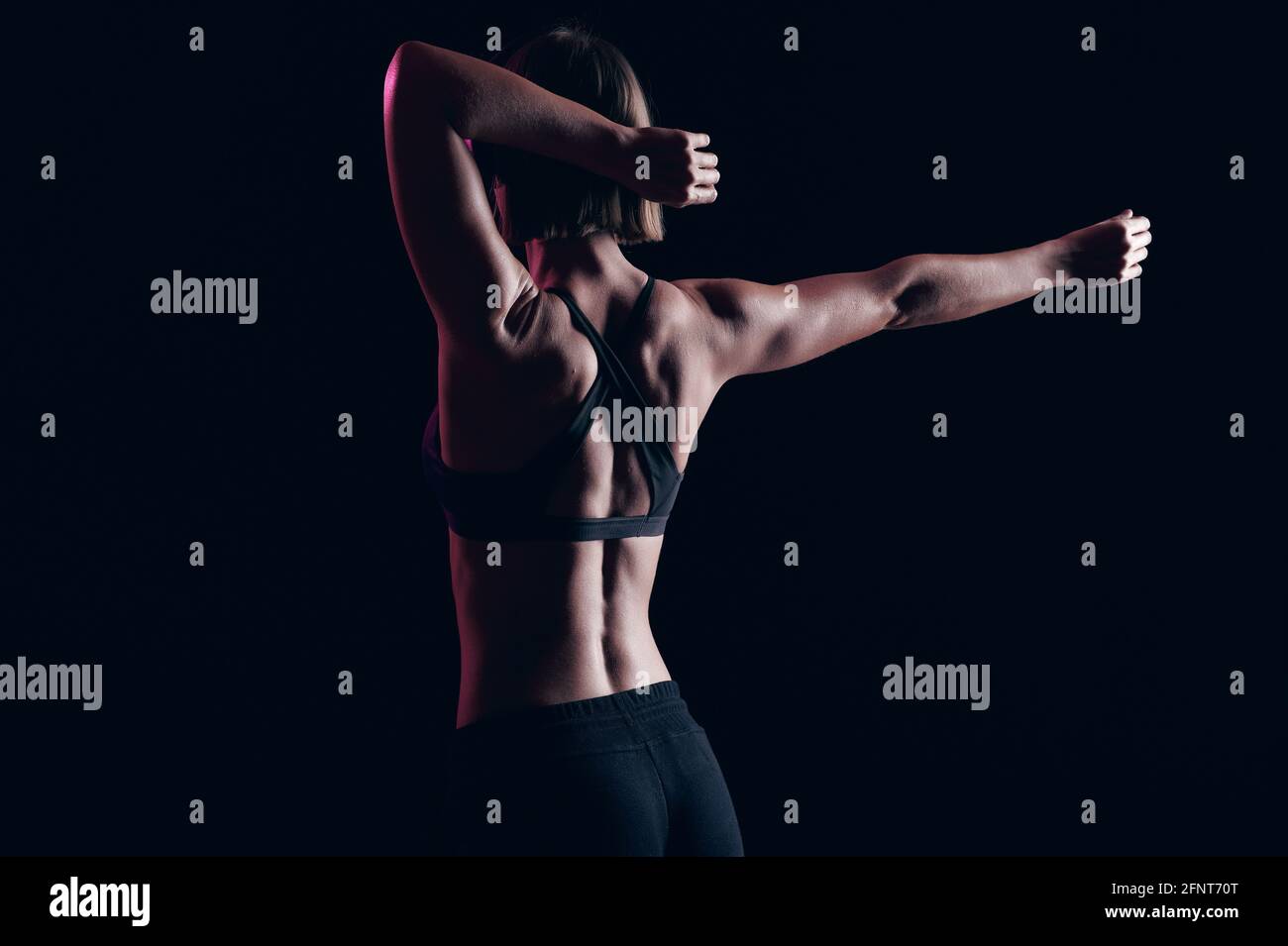 Stretching vor dem Training. Muskulöse Mädchen mit starken Armen und abs hören Musik in Kopfhörer. Gesunder Lebensstil Stockfoto