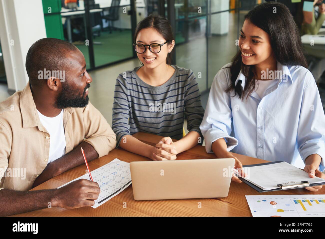 Drei freundliche Bürokollegen, die bei der Arbeit miteinander sprechen Stockfoto