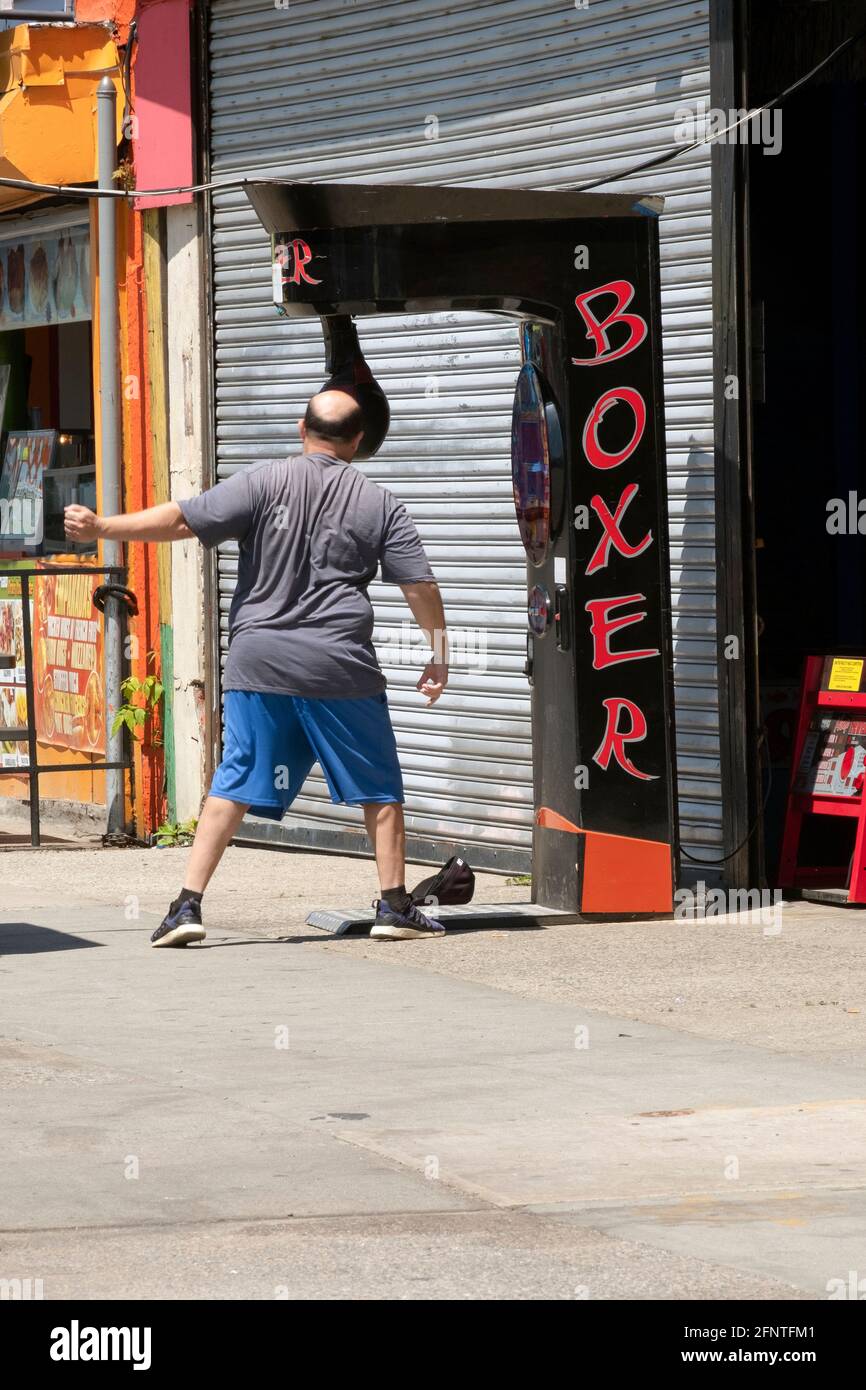 Ein anonymer kahler Mann mittleren Alters entlastet den Stress, indem er an einem Boxsack schwingt. In Coney Island, Brooklyn, New York. Stockfoto