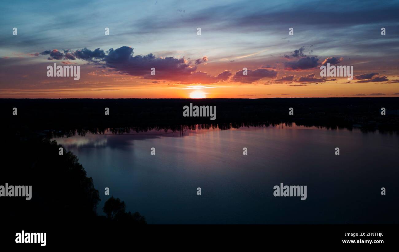 Schöner Sonnenuntergang mit Wolken über dem Fluss unter Bau Häuser in der Dunkelheit, Ukraine, Kiew am 6. Mai. Stockfoto