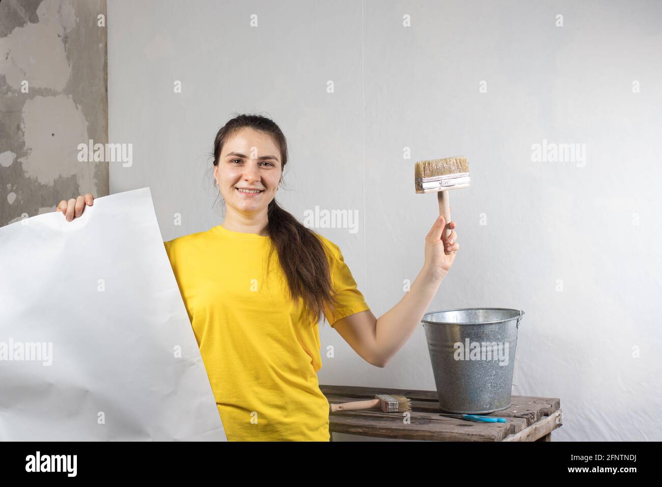 Eine Reparaturfrau klebt weiße Tapeten an die Wand. Reparaturarbeiten, Tapezieren. Platz für Textkopie. Stockfoto