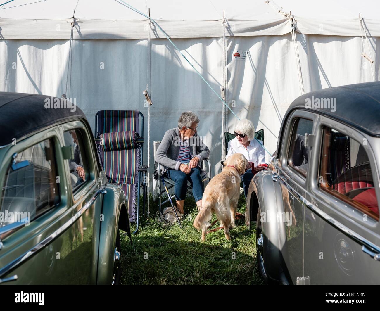 Zwei Frauen diskutieren auf der Melplash Agricultural Society Show auf dem West Bay Show Grounds, Bridport, Dorset, unter ein paar Oldtimern Stockfoto