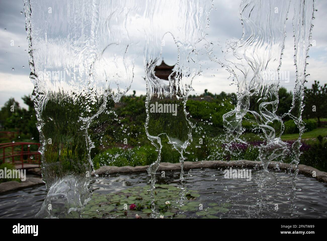 Wasserfall gegen den Himmel. Das fallende Wasser ist im Bild gefroren. Kühle Aufnahme von Wasserspritzern. Stop Rahmen eines kleinen Wasserfalls in einem Park. Stockfoto