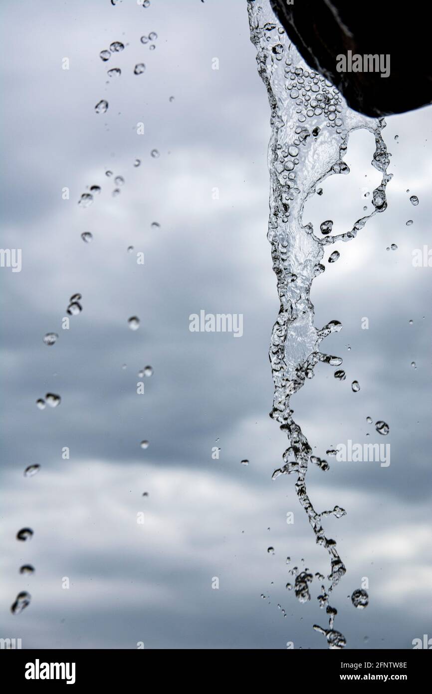 Wasserfall gegen den Himmel. Das fallende Wasser ist im Bild gefroren. Kühle Aufnahme von Wasserspritzern. Stop Rahmen eines kleinen Wasserfalls in einem Park. Stockfoto