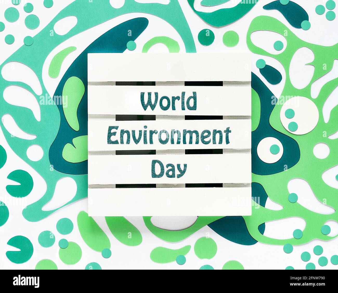 Weltumwelttag. Abstrakte fließende Formen, Papierkunst in Grüntönen. Off White Concept Background, monochromer Look. Holzpalette mit Text Stockfoto