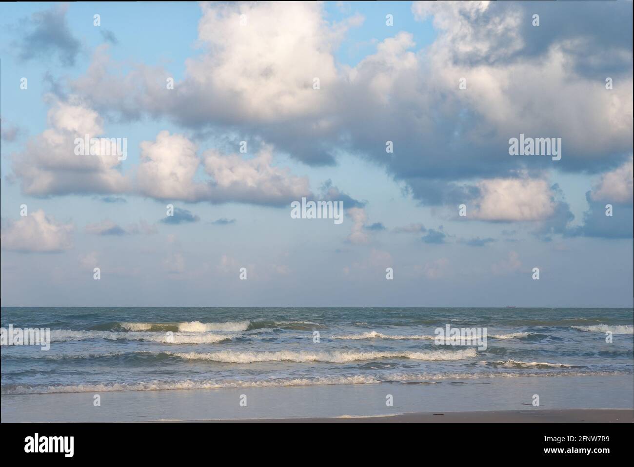 Der kalmütige Strand am Meer dämmerte den Sonnenuntergang mit hellblauem Himmel und wehenden Wellen. Stockfoto
