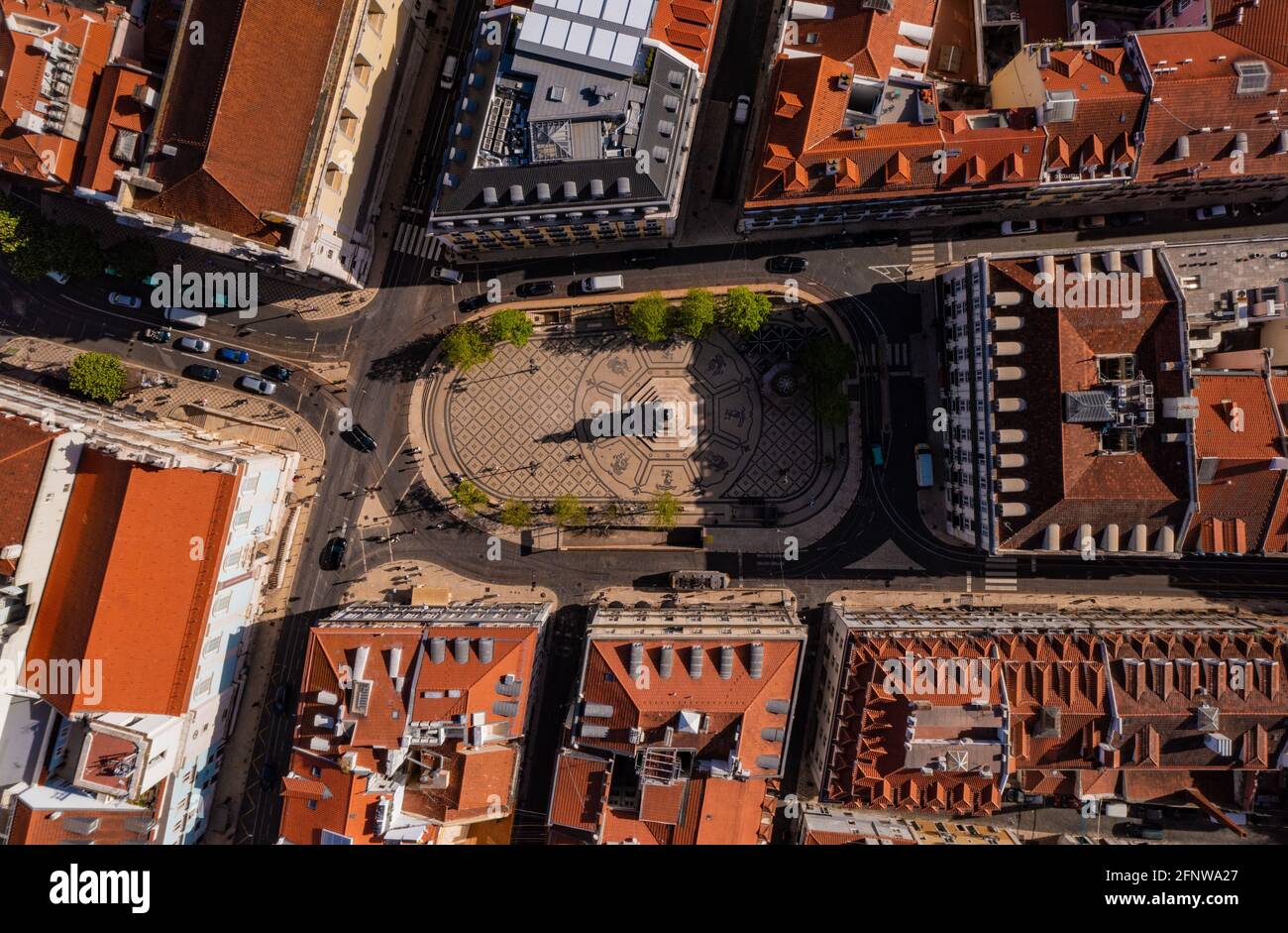 Blick von oben auf den Marktplatz in Lissabon, Portugal. Dekorativer gefliester Boden mit Ornamenten und Statue auf achteckigem Sockel, der mit einer Straße gesäumt ist. Stockfoto