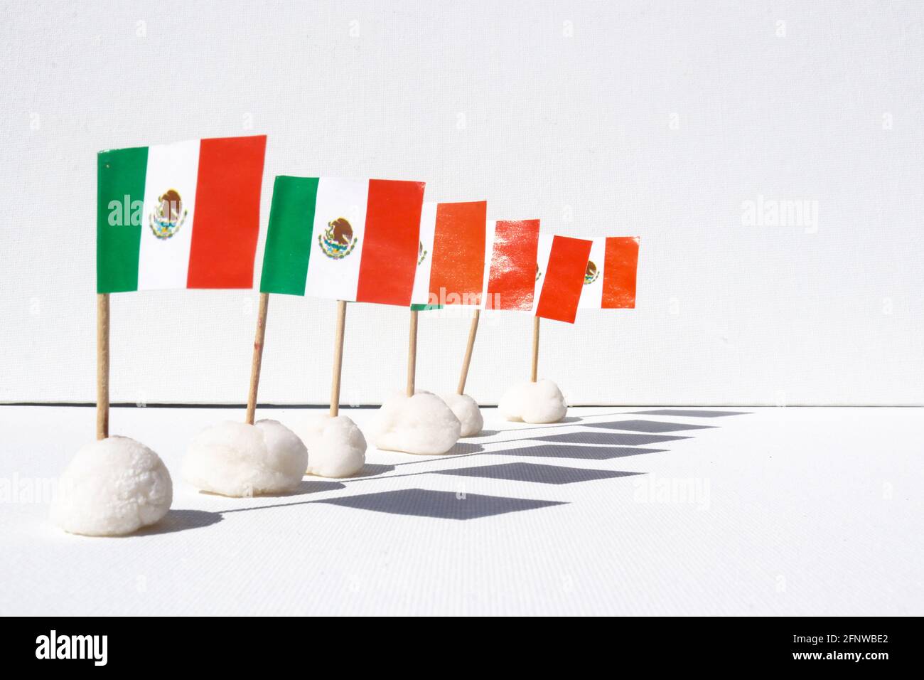 Eine Reihe von mexikanischen Mini-Flaggen mit Schatten auf einem Weißer Leinwandhintergrund Stockfoto