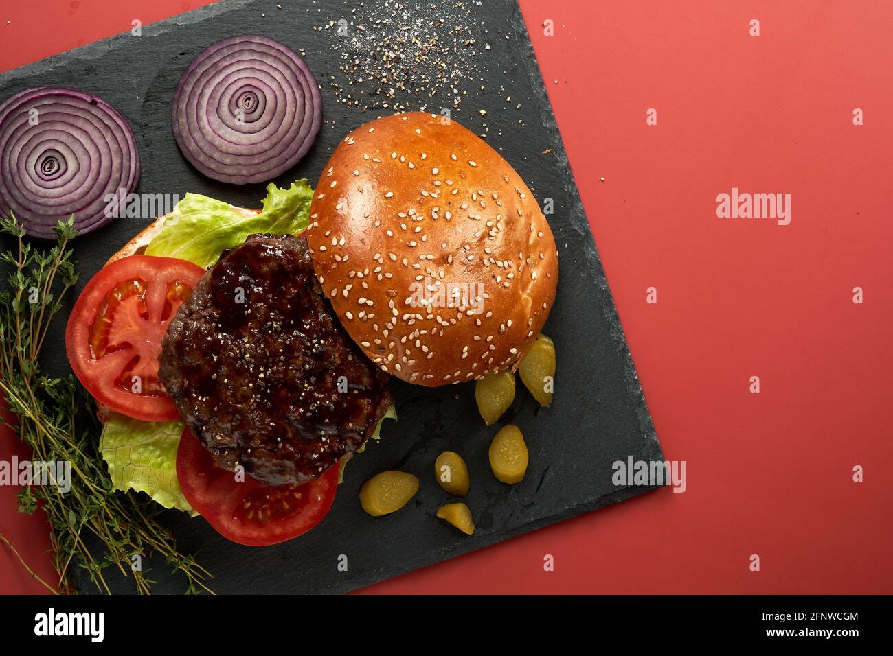 Hamburger auf einem schwarzen Brett Flatlay. Roter Hintergrund. Flatlay. Stockfoto