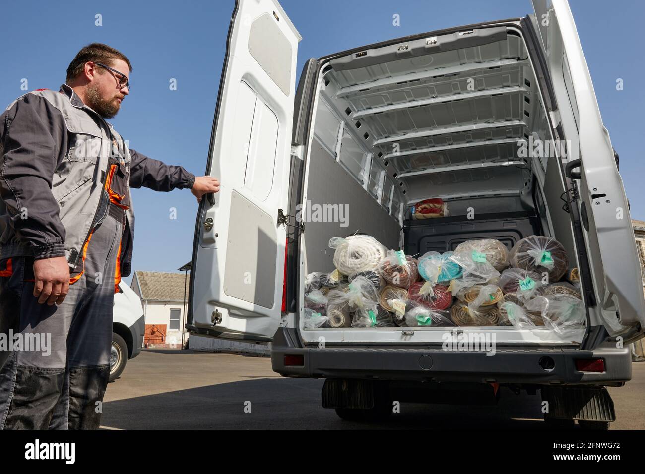 Arbeiter, der in der Nähe eines LKW voller Teppiche steht. Reinigungskonzept Stockfoto