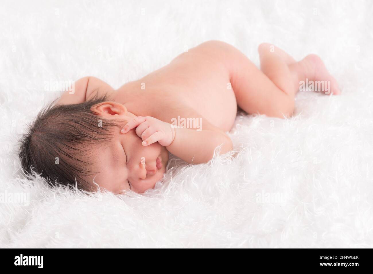 Nette neugeborene Baby Junge schlafen Gesicht nach unten auf einem weichen weißen flauschigen Tuch. Stockfoto