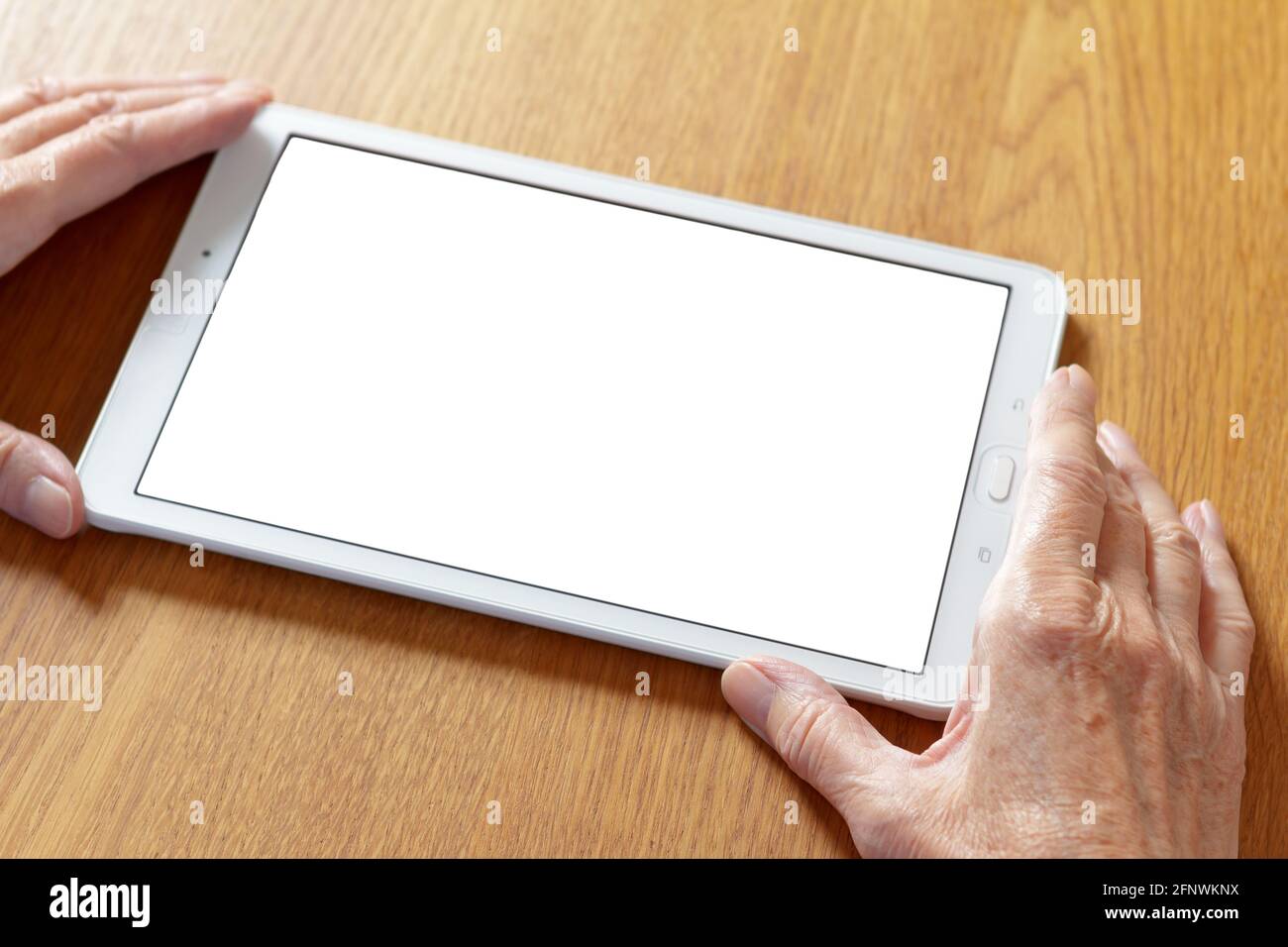 Online-Video-Telefonanruf: Hände einer alten Frau, die einen Tablet-Computer mit einem weißen Bildschirm hält. Stockfoto