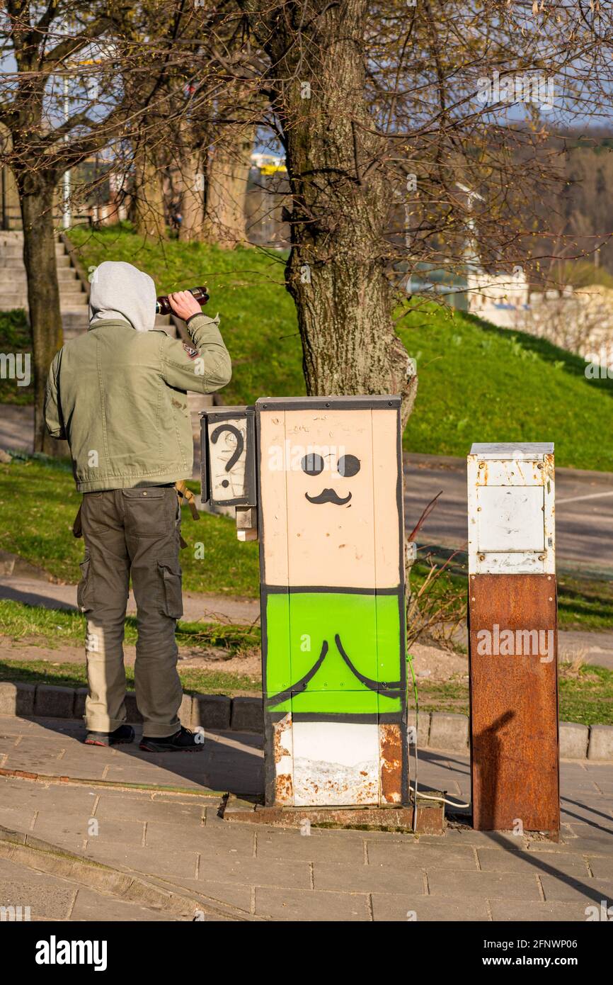 Betrunkener Mann trinkt aus einer Flasche auf der Straße in der Stadt, vertikal Stockfoto