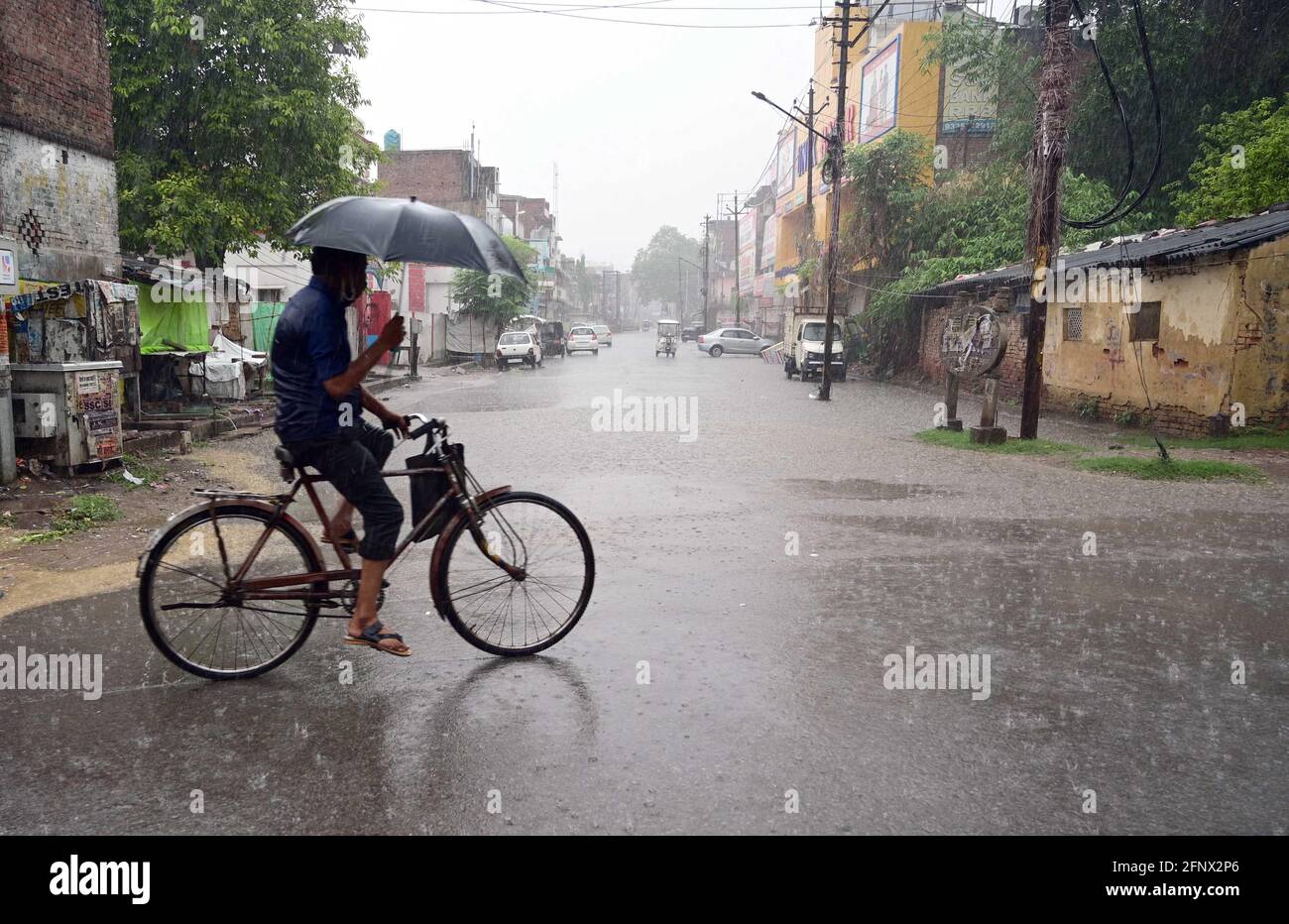 Prayagraj, Uttar Pradesh, Indien. Mai 2021. Prayagraj: Ein Radfahrer benutzt einen Regenschirm, um am Mittwoch, den 19. Mai 2021, vor einer Regendusche in Prayagraj sicher zu sein. Quelle: Prabhat Kumar Verma/ZUMA Wire/Alamy Live News Stockfoto