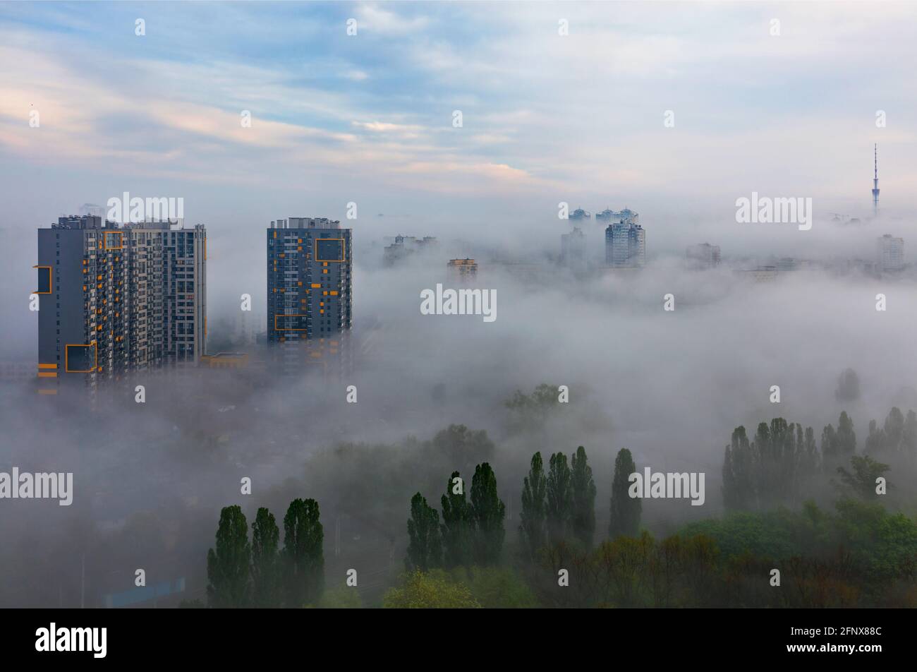 Ein nebliger Morgen umhüllte die schlafende Stadt Kiew, Wohnhochhäuser und einen grünen Park mit Blick auf den blauen Himmel. Stockfoto