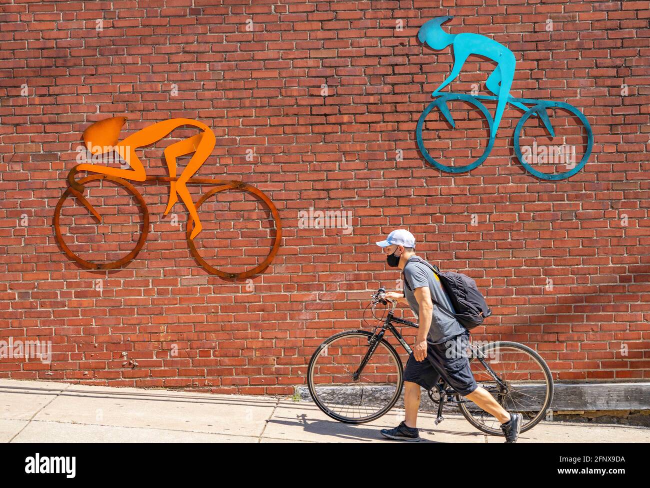 Philadelphia, Pennsylvania, USA. Mai 2021. Roberto Lopez-Martinez, 33, aus  Philadelphia, Pennsylvania, beschließt, sein Fahrrad am Mittwoch einen  Hügel hinauf zu laufen, trotz der Inspiration an der Wand eines  Unternehmens in Manayunk, einem