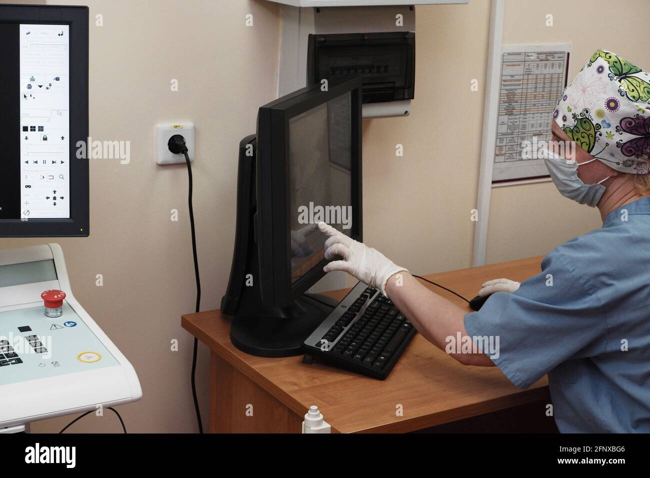 Eine Radiologin hinter dem Monitor führt eine Röntgenkorrektur durch. Stockfoto