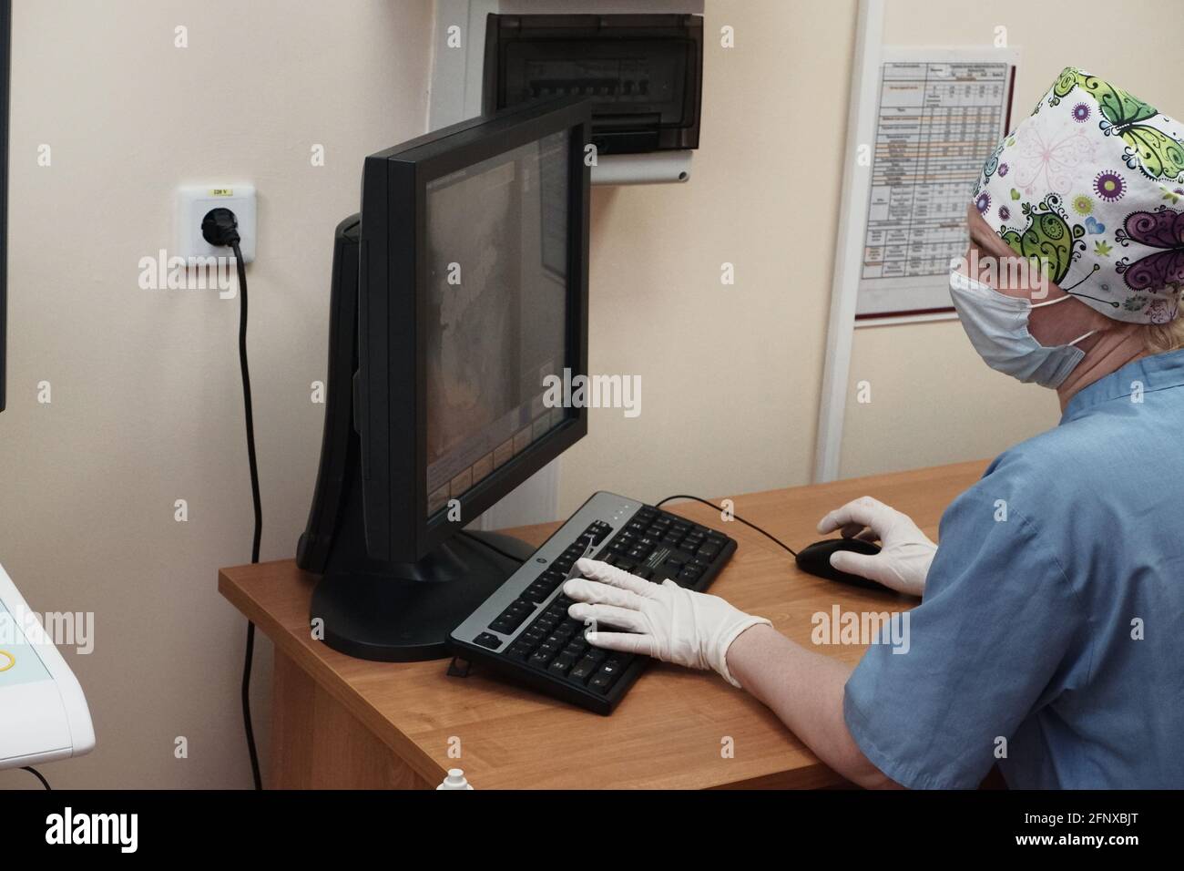 Eine Radiologin hinter dem Monitor führt eine Röntgenkorrektur durch Stockfoto