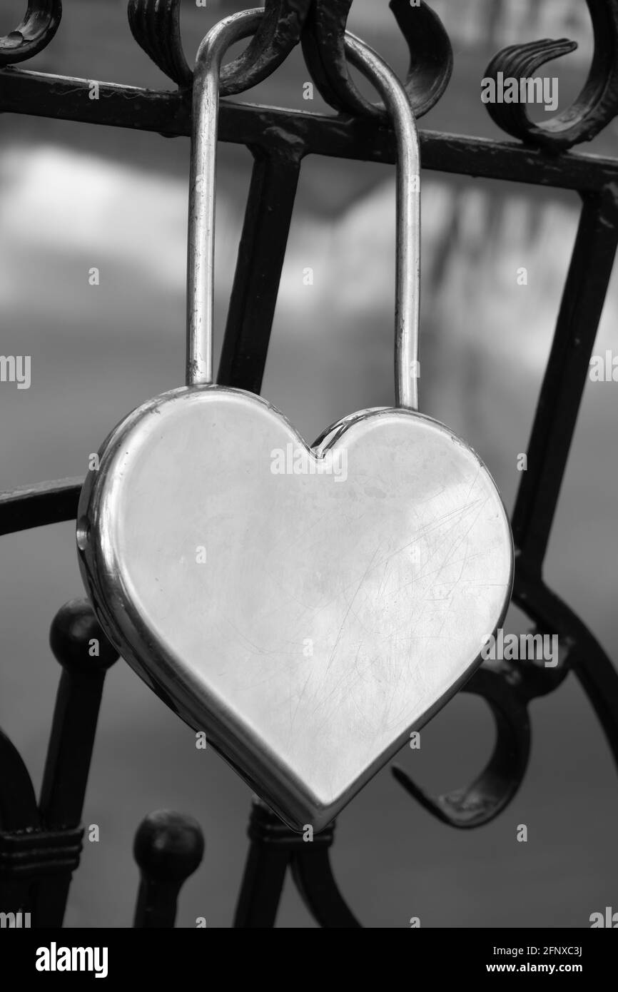 Türschloss aus Metallsilber in Form eines Herzens am Zaun als Symbol ewiger Liebe. Stockfoto
