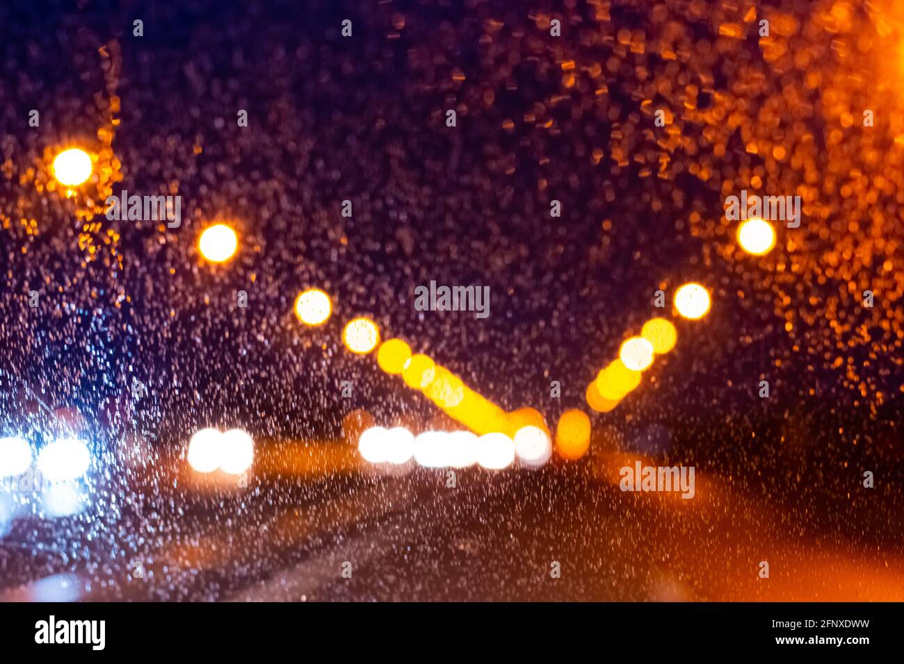 Nasse Spur in der Nacht mit der Aussicht auf Beleuchtung Lichter entlang der Straße in einer regnerischen Nacht, verschwommener Hintergrund, kopieren Raum Stockfoto