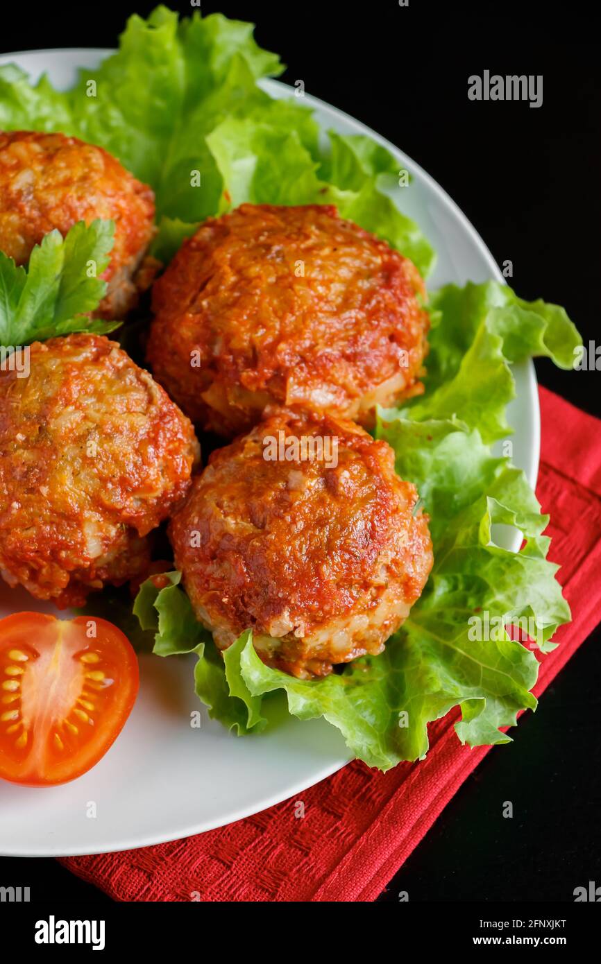 Fleischbällchen in Tomatensauce auf schwarzem Hintergrund. Hausgemachte Protein-Mahlzeit für eine gesunde Ernährung. Stockfoto