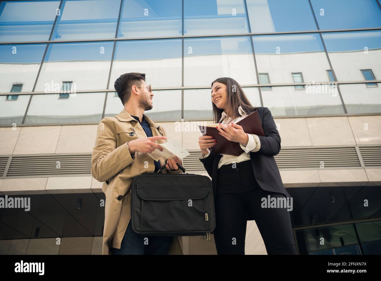 Zwei Geschäftsleute lachen vor dem Unternehmen Stockfoto