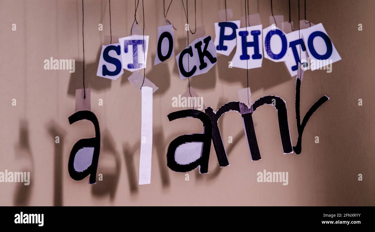 An Fäden hängende Buchstaben bilden in einer gewissen Unordnung das Alamy-Logo. Stockfoto