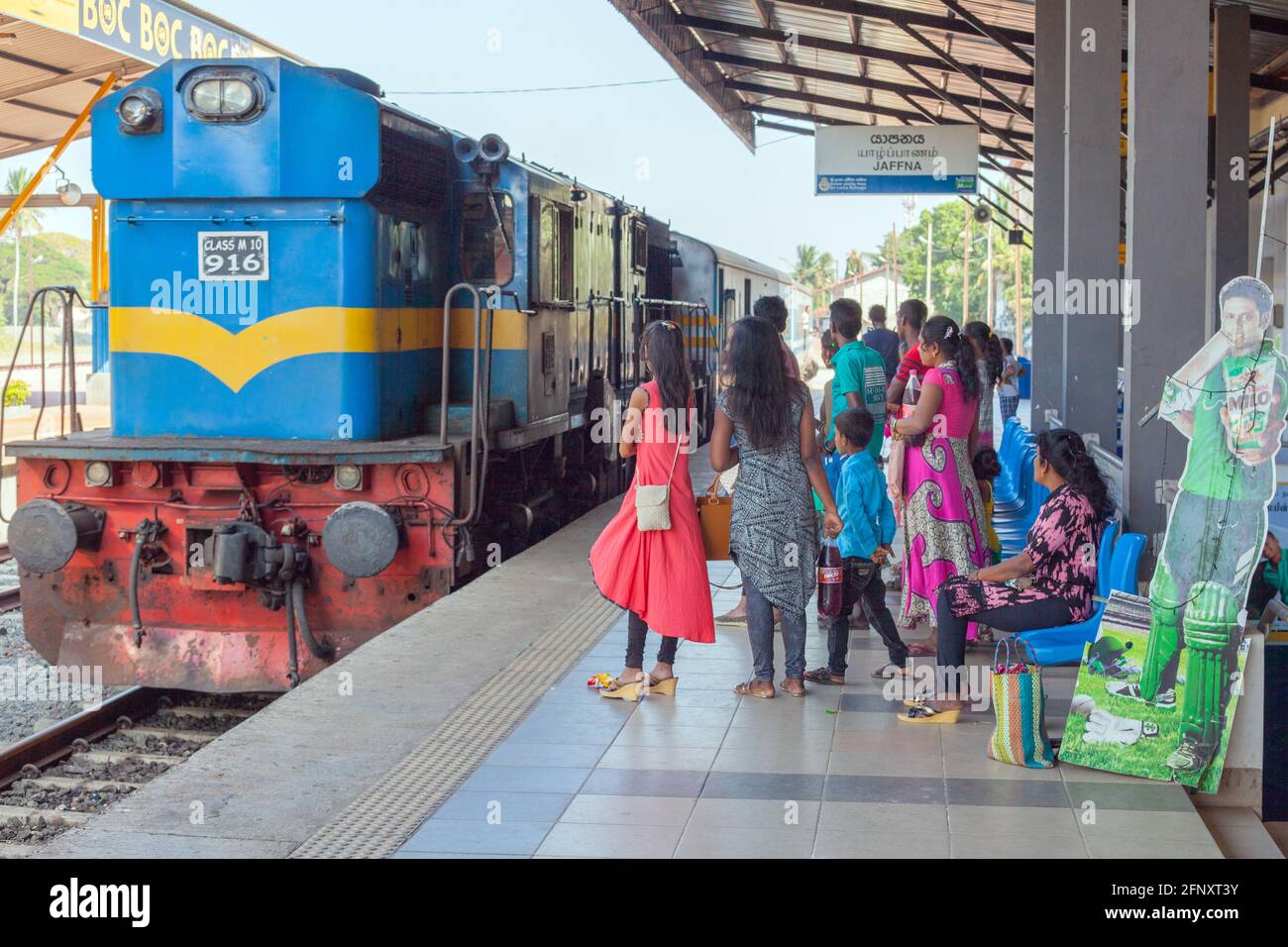 Sri-lankische Familie wartet auf die dieselelektrische Lokomotive der Klasse M10 916, die am Bahnhof Jaffna in Sri Lanka in die Plattform einfährt Stockfoto