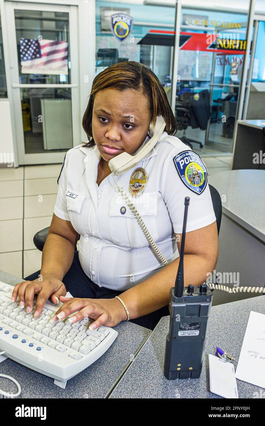 North Miami Beach Florida, Polizeibehörde, schwarze Frau weibliche Offizier Computer Dispatcher Mitarbeiter arbeiten, Tastatur Telefon zwei 2-Wege-Radio, Stockfoto