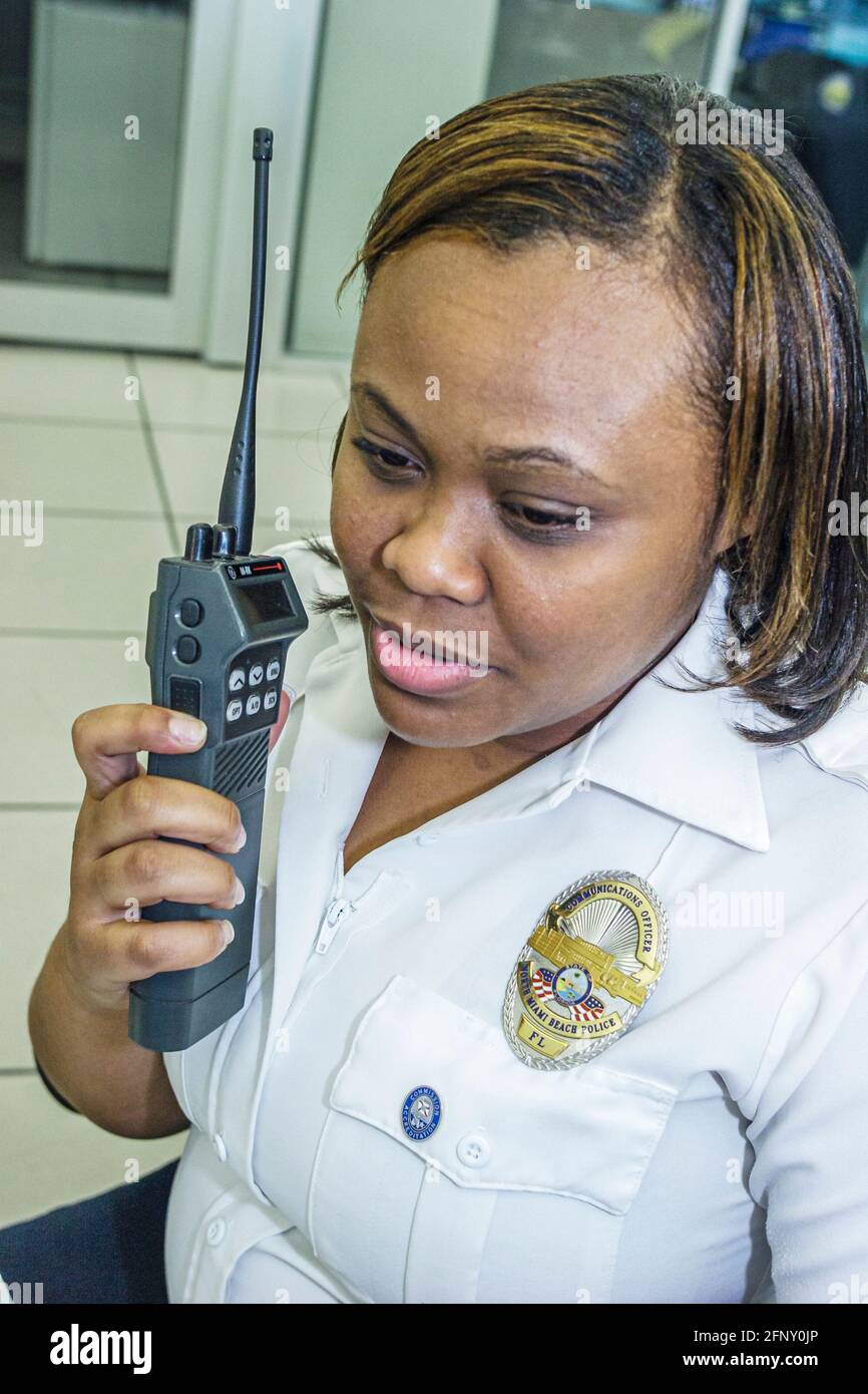 North Miami Beach Florida, Polizeibehörde, schwarze Frau weibliche Offizier Dispatcher Mitarbeiter arbeiten mit zwei 2-Wege-Radio, Stockfoto