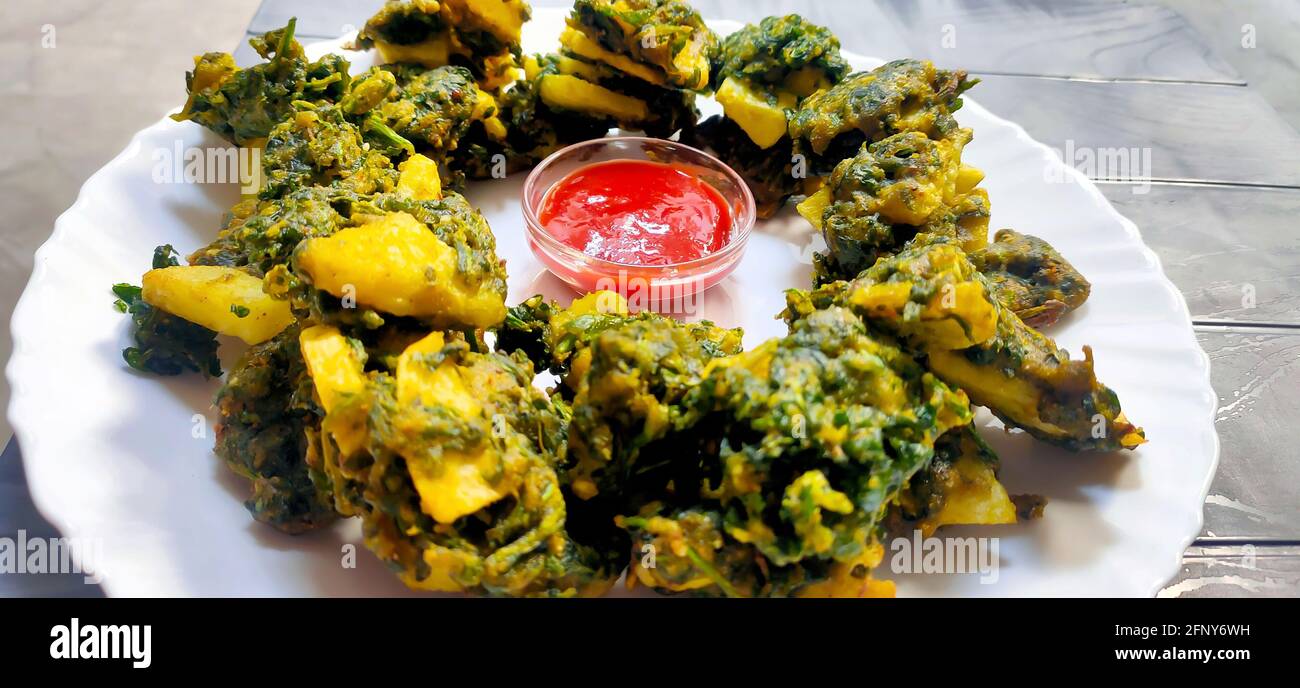 Spinat- und Kartoffelpakoras mit Sauce, ein äußerst leckerer und leckerer Snack der pakistanischen und indischen Völker Stockfoto