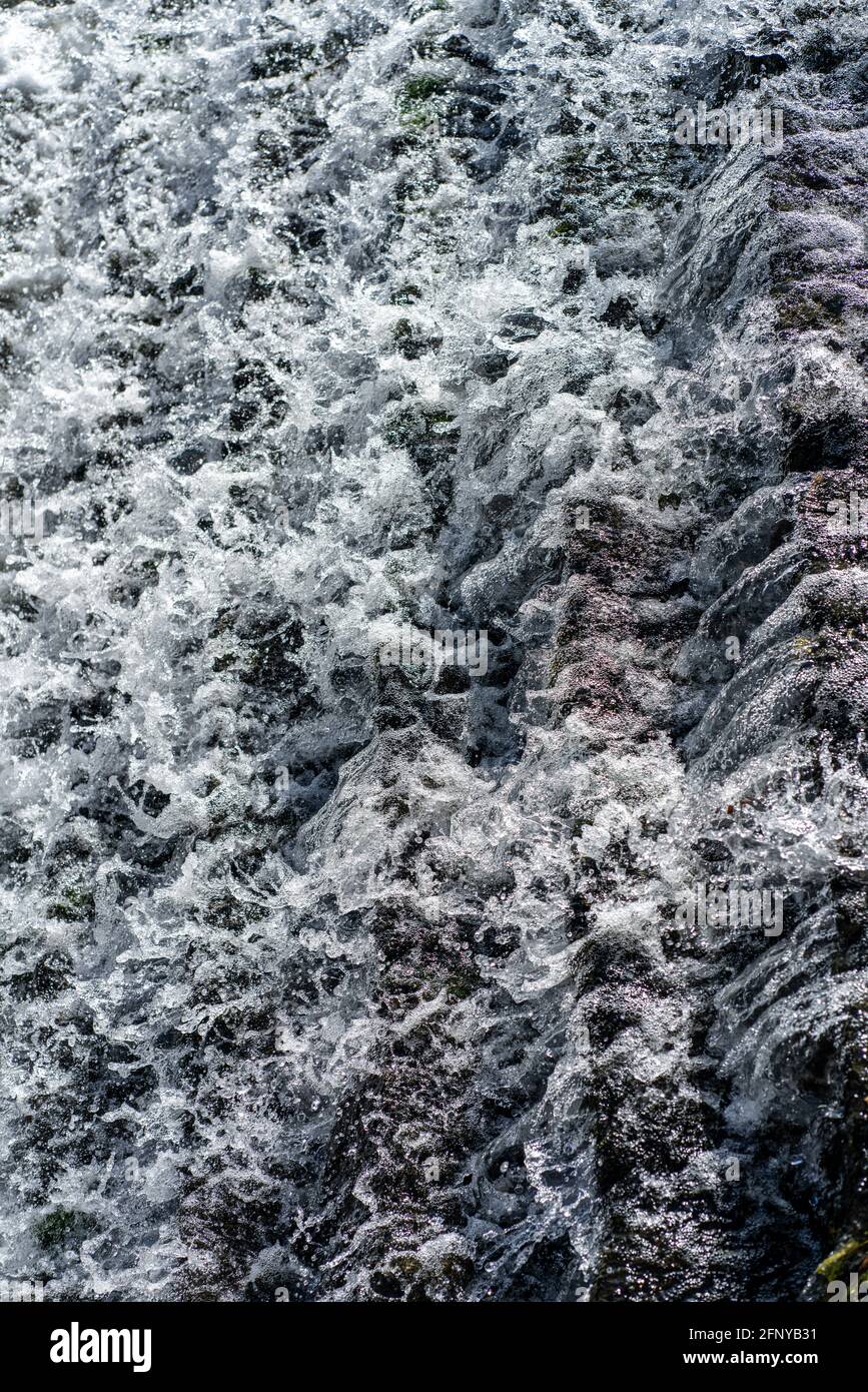 Frisches Wasser aus einem Fluss fließt einige Stufen hinunter, die einen Damm bilden. Stockfoto