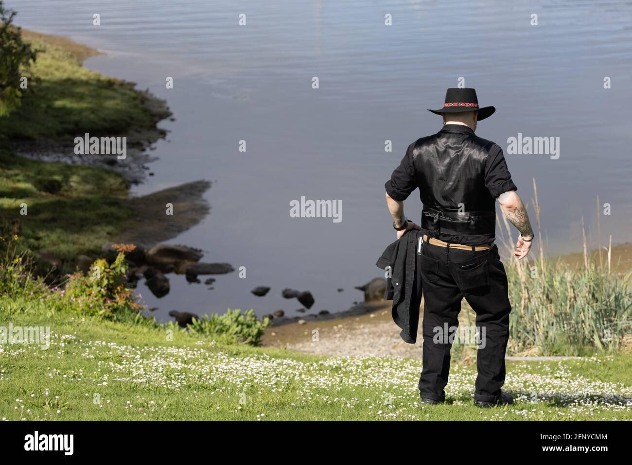 Mann mit schwarzem Outfit und Hut genießt einen Spaziergang Stockfoto