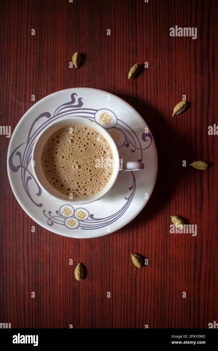 Blick von oben auf eine Tasse indischen Masala-Tee mit einigen Kardamom auf einem Holzhintergrund Stockfoto