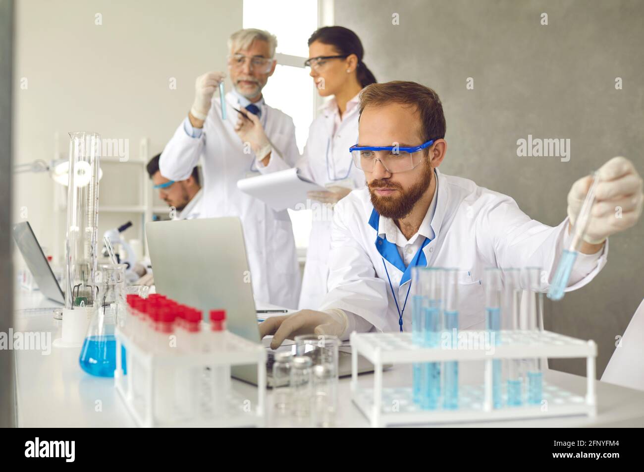 Fokussierter männlicher Wissenschaftler in Schutzbrillen, der medizinische Forschung in macht Labor Stockfoto
