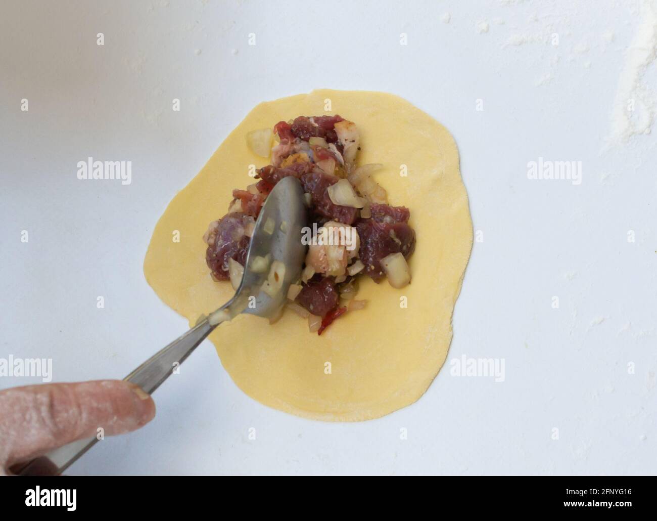 Frauenhände Rollen den Teig mit einem Nudelholz aus. Der traditionelle Sambus Herd. Das Konzept des Kochens in der Natur. Stockfoto