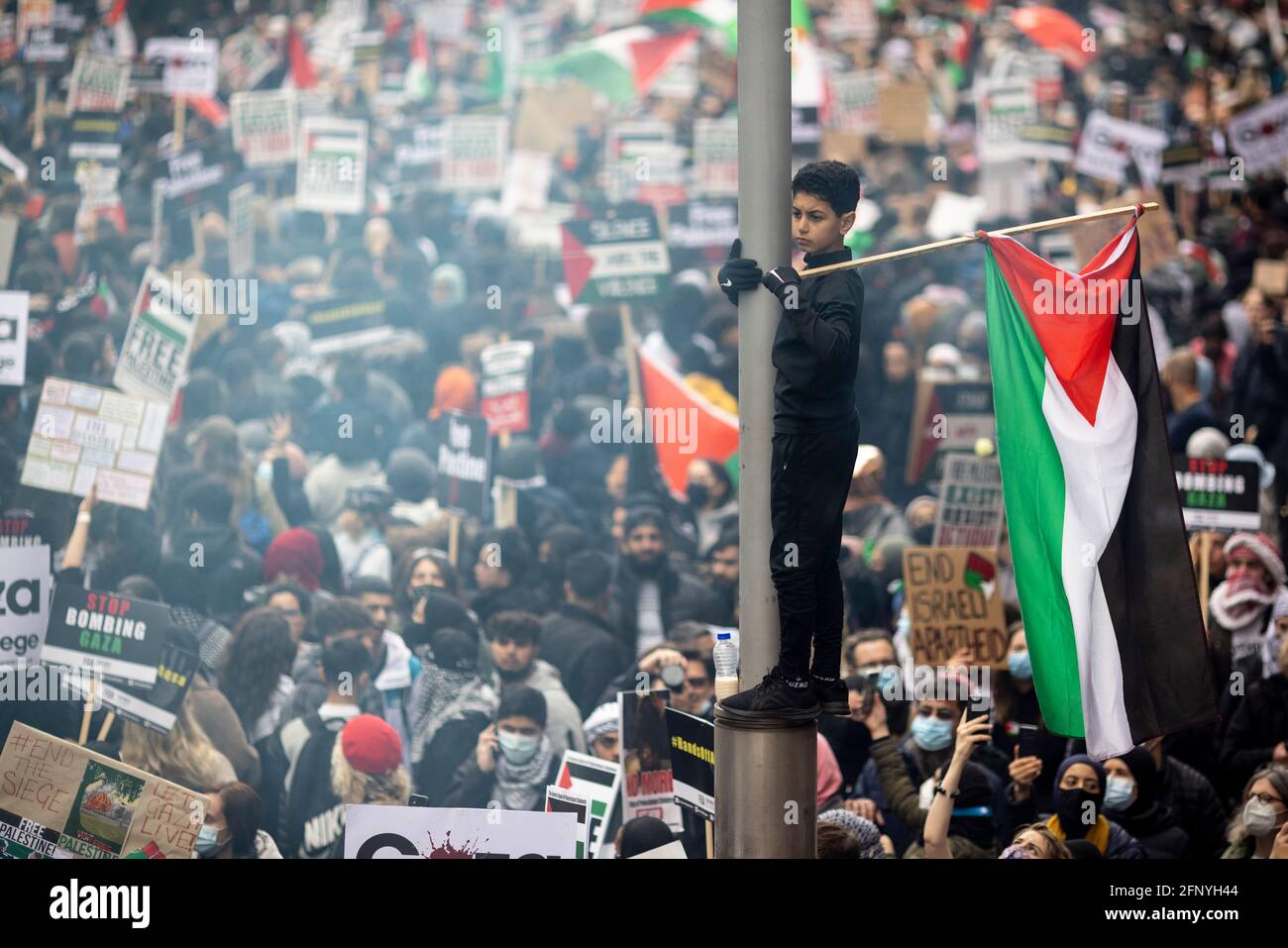 Junger Junge schwingt palästinensische Fahne über die Menschenmenge, Solidaritätsprotest „Freies Palästina“, London, 15. Mai 2021 Stockfoto