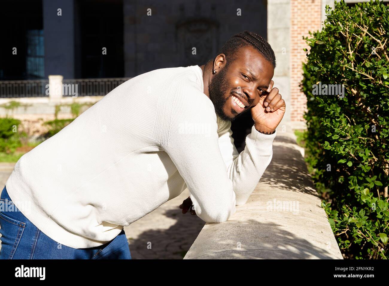 Junger afroamerikanischer Mann, lächelnd, gelehnt an eine Wand, glücklicher Latino-Mann. Hochwertige Fotos Stockfoto