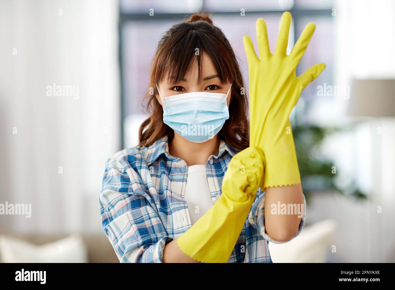 asiatische Frau in Schutzmaske und Gummihandschuhe Stockfoto