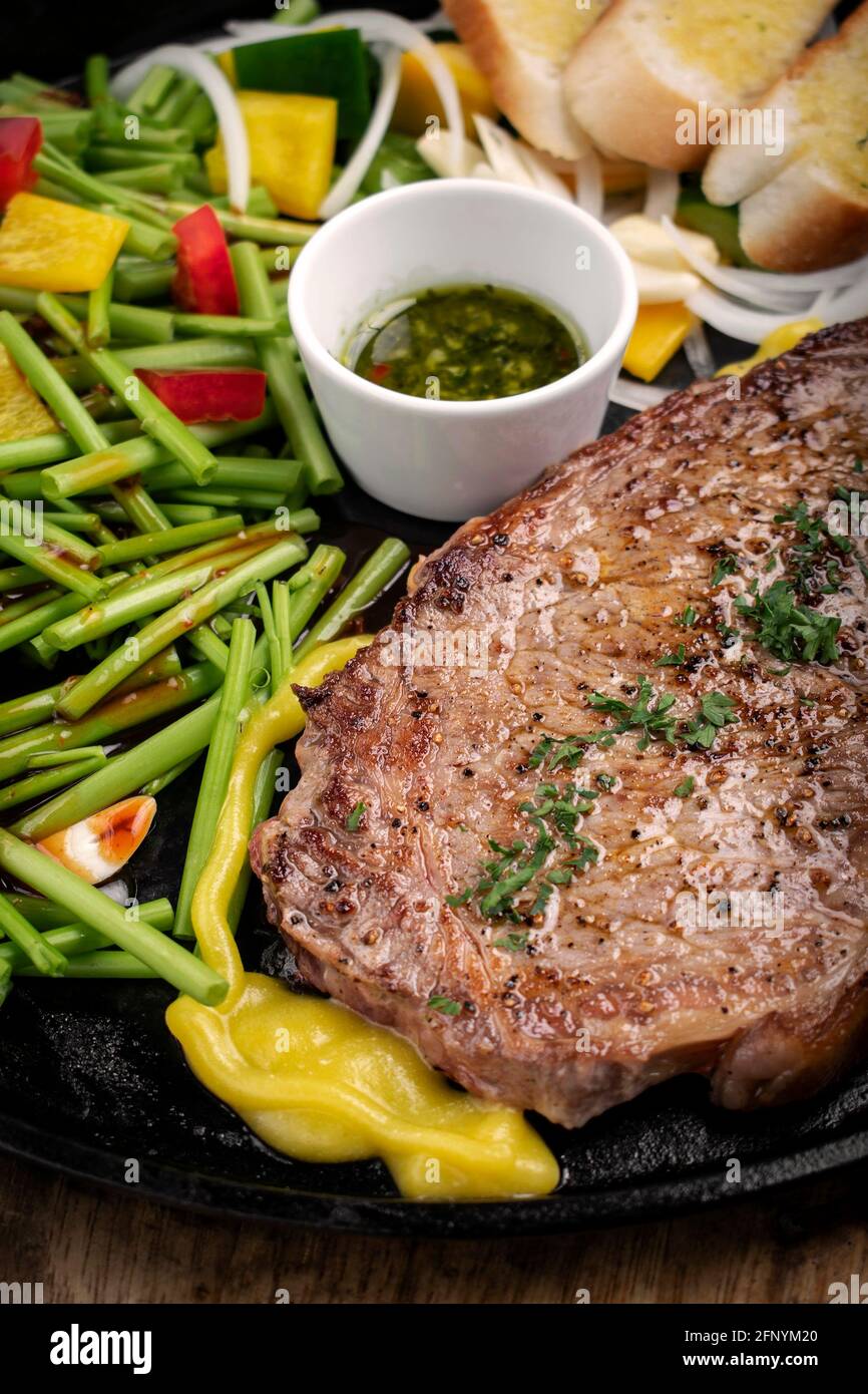 Bio-Rinderfilet-Steak-Sizzler auf heißer Platte Mit gemischtem Gemüse und Chimichurri-Sauce Stockfoto