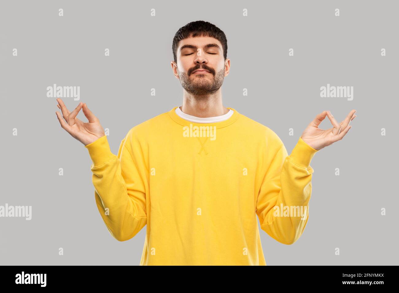 Junger Mann im gelben Sweatshirt meditiert Stockfoto