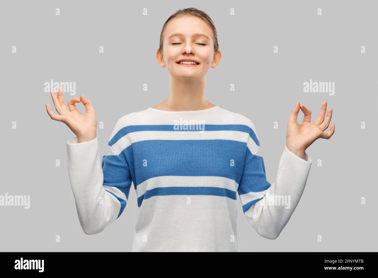 Glücklich lächelndes Teenager-Mädchen im Pullover meditieren Stockfoto