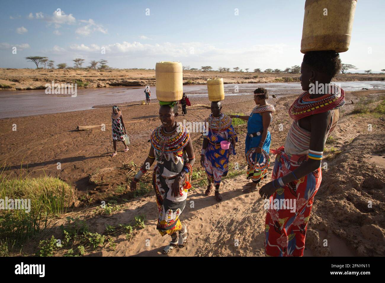 Am 19. Februar 2015 gehen Frauen zurück ins Dorf Umoja, nachdem sie Wasser aus einem nahegelegenen Fluss, Samburu, Kenia, gesammelt haben. Stockfoto