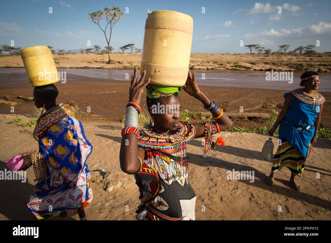 Am 19. Februar 2015 gehen Frauen zurück ins Dorf Umoja, nachdem sie Wasser aus einem nahegelegenen Fluss, Samburu, Kenia, gesammelt haben. Stockfoto